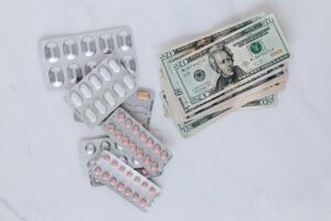 set of pills with heap of paper money